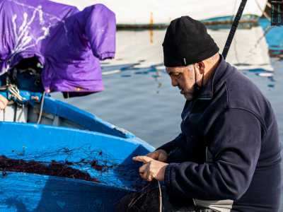 ...uno dei quali ospita un altro anziano lavoratore del mare intento a tagliare una rete
